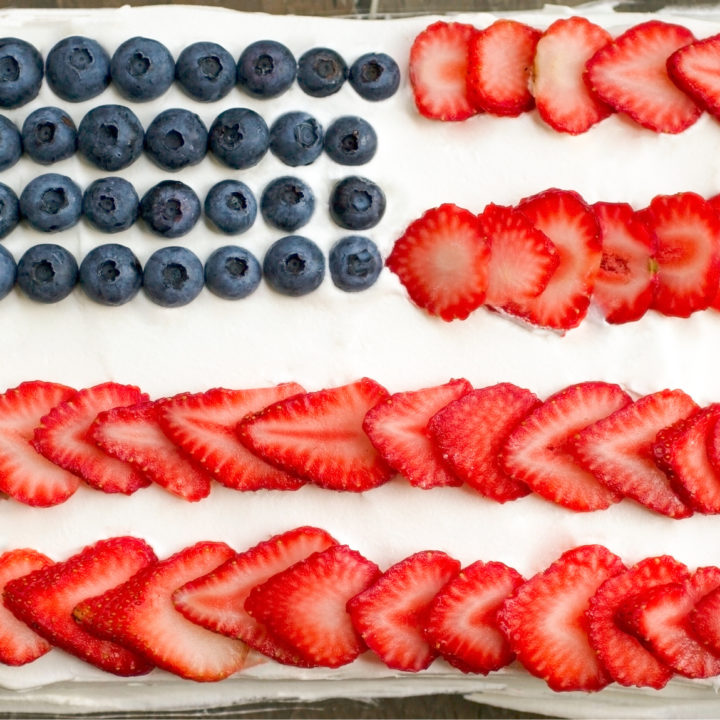 keto patriotic poke cake made in the shape of an American flag using blueberries and sliced strawberries.