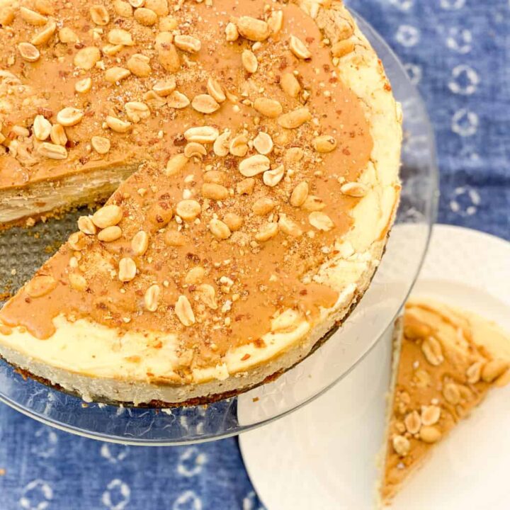 keto peanut butter swirl cheesecake featured image shows a cheesecake on a clear stand with a slice removed