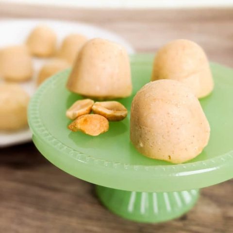 Peanut Butter Cream Cheese Fat Bombs on Green Pedestal with Peanuts