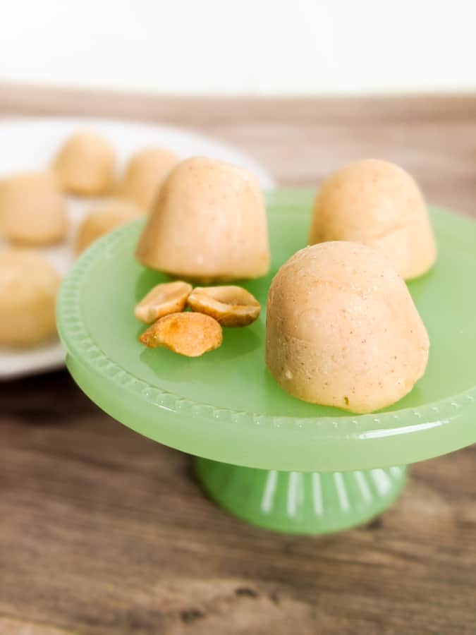 Peanut Butter Cream Cheese Fat Bombs on Green Pedestal with Peanuts