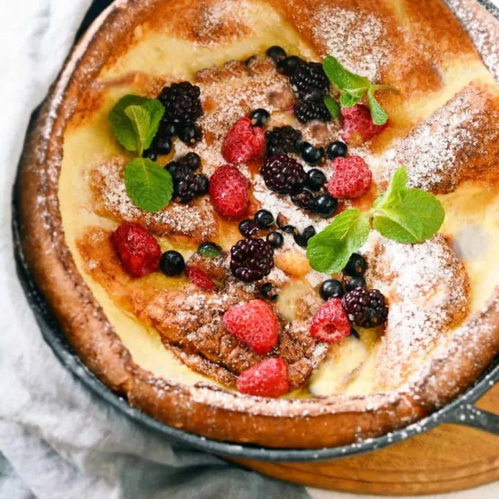 keto Dutch baby pancake baked in a cast-iron skillet and topped with fresh berries