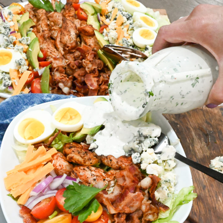 keto Cobb salad with blue cheese dressing being poured on top