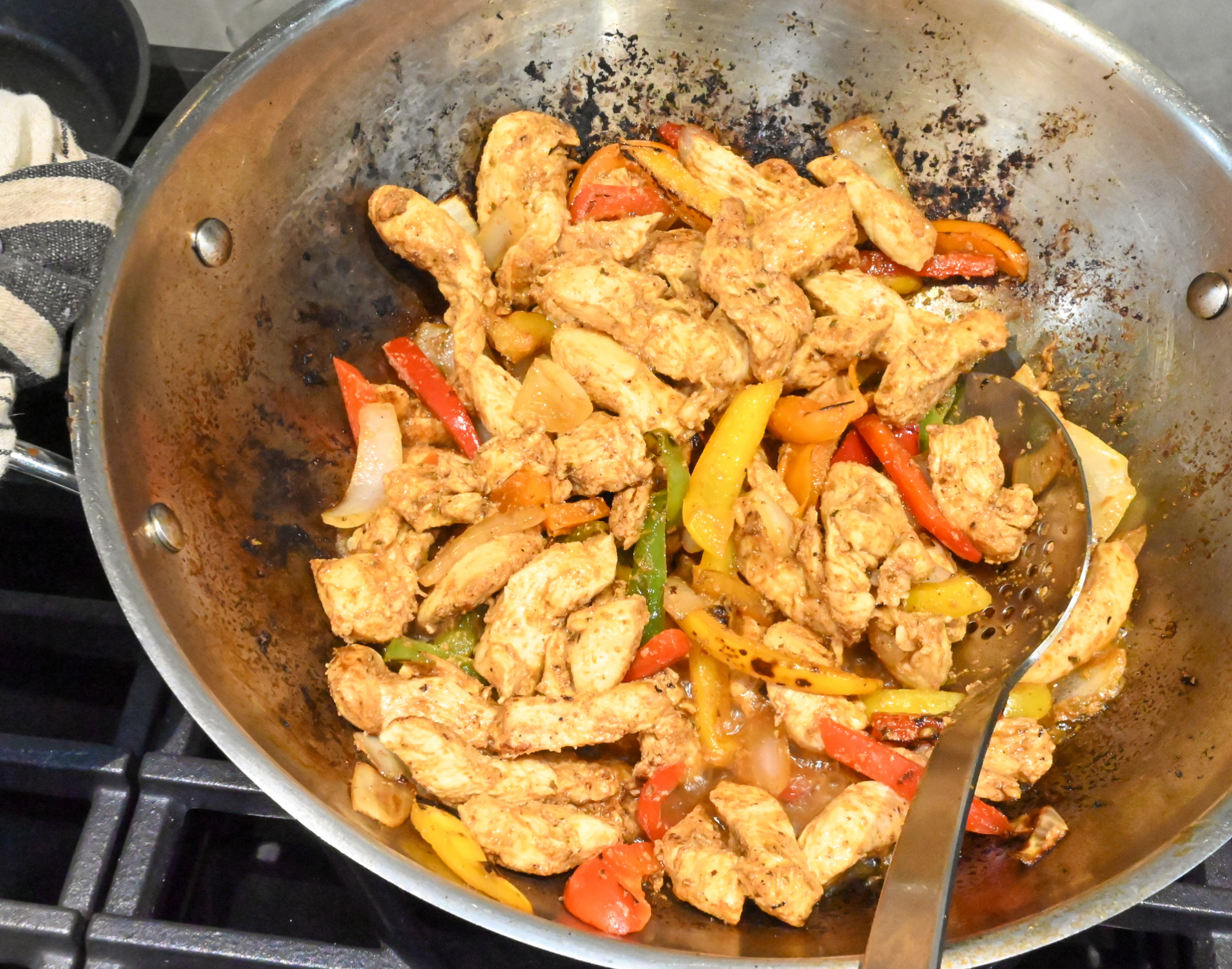 chicken fajitas being cooked in a large wok