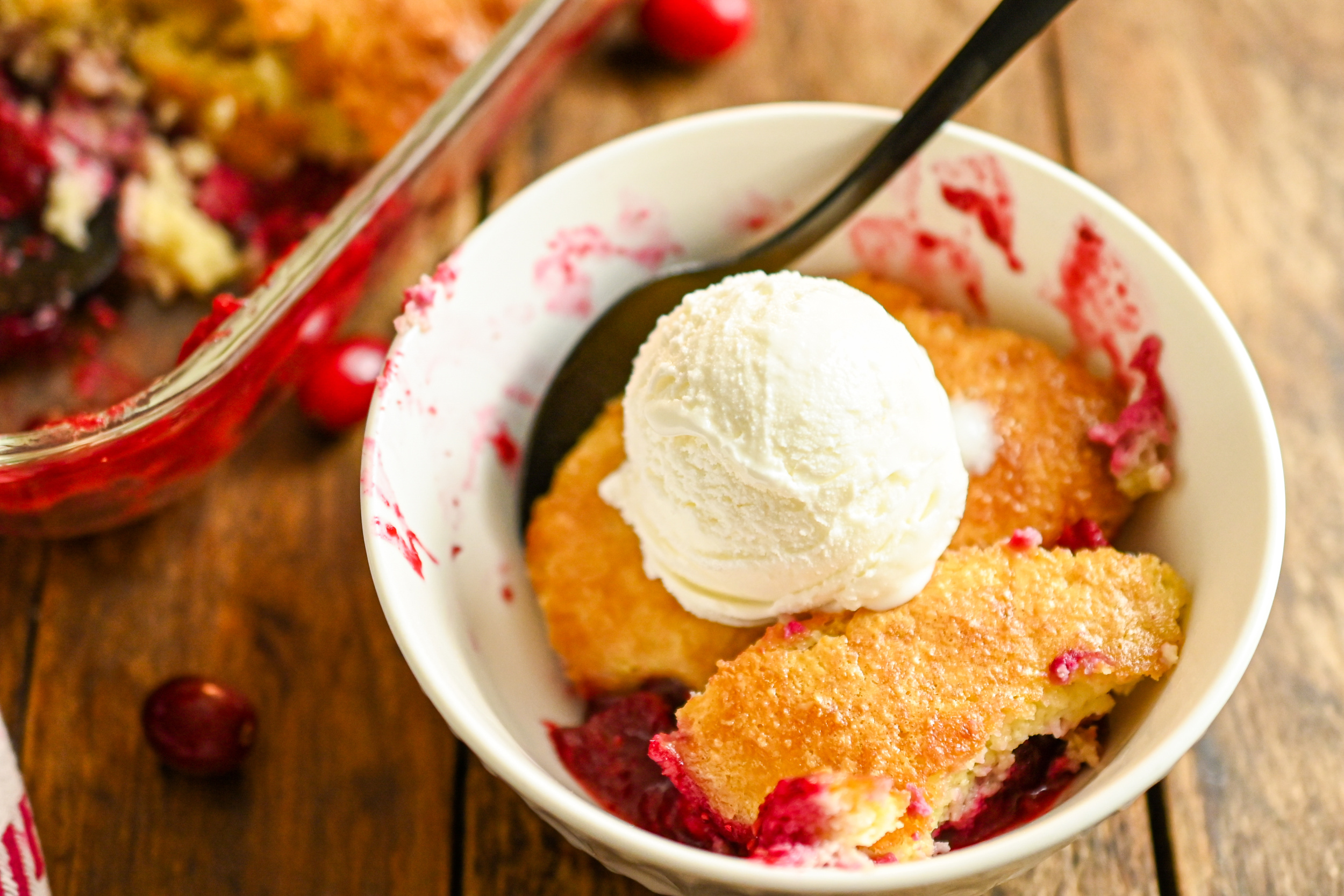 Keto cranberry cobbler served in a small white plate with a scoop of keto vanilla ice cream