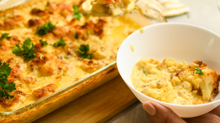 keto cauliflower mac and cheese being served into a white bowl