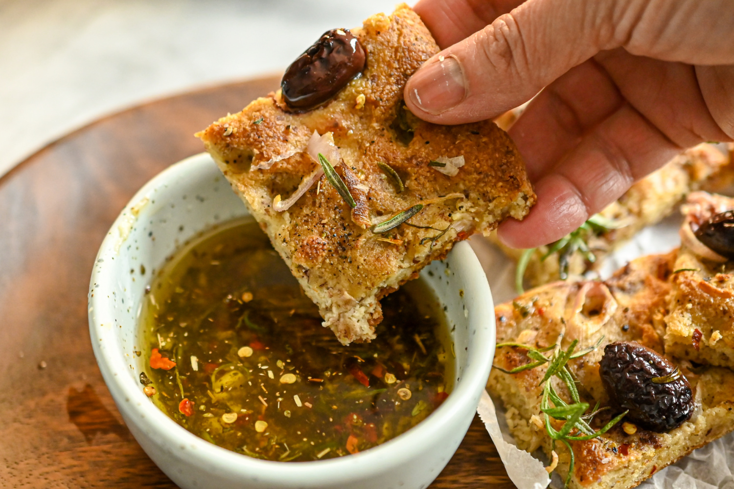 keto focaccia being dipped in seasoned olive oil dip