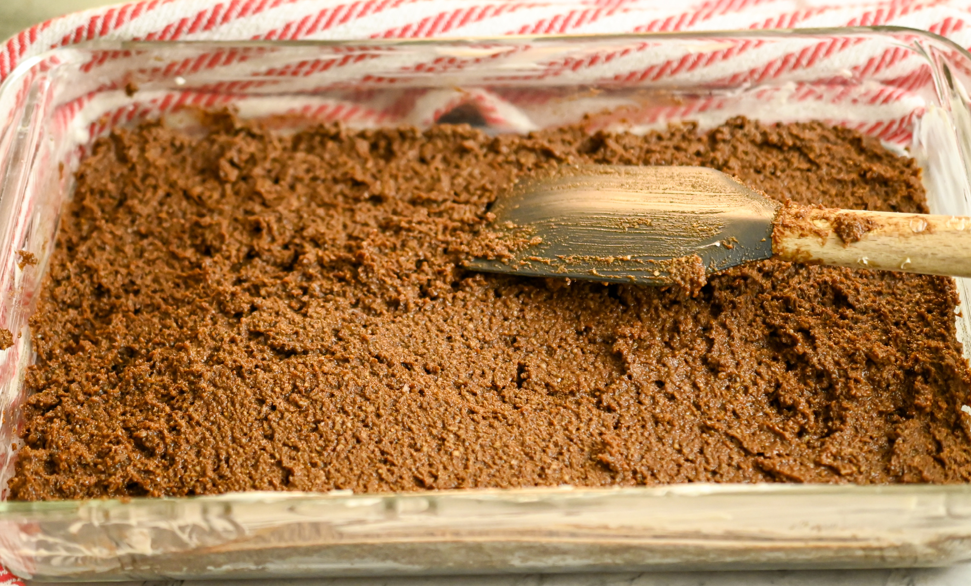 keto gingerbread cake being spread into a rectangle container