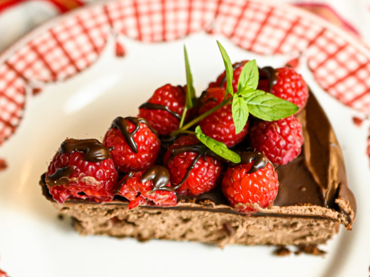 Slice of keto chocolate raspberry cheesecake served on a white and red plate