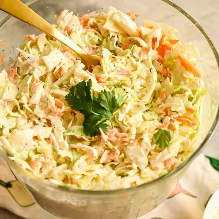Keto Coleslaw served in a clear salad bowl with a gold serving spoon