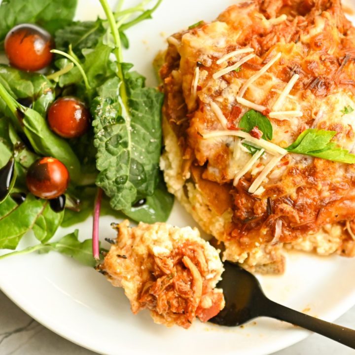 keto chicken lasagna served on a white plate with a green salad