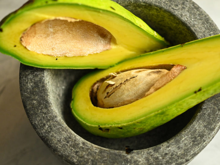 Florida avocado sliced in half inside a large grey mortar