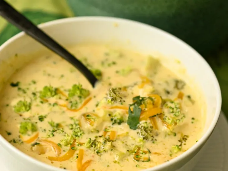 keto broccoli cheese soup made in a slow cooker and served in a white bowl with a black spoon