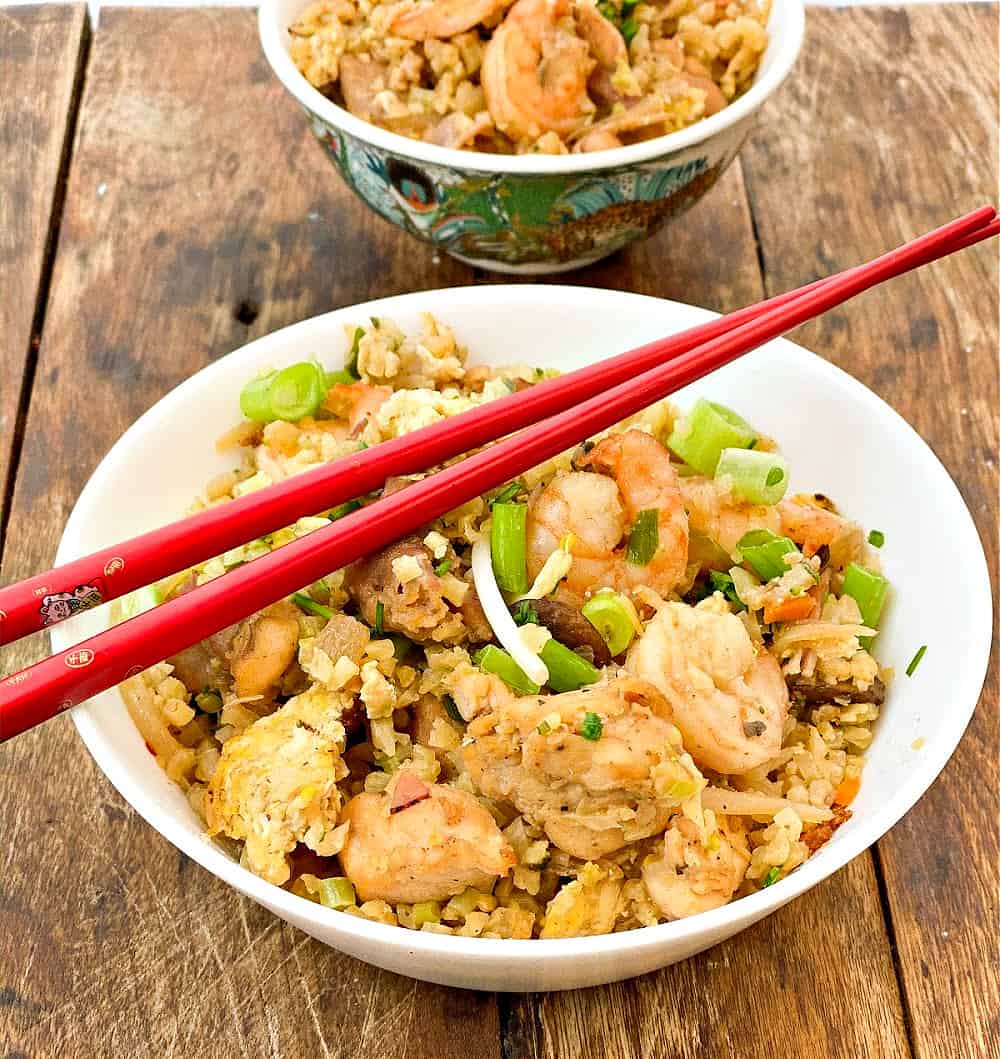 easy keto fried rice close up in a large white bowl and a small teal bowl