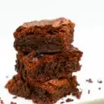 keto coconut flour brownies stacked on a white plate