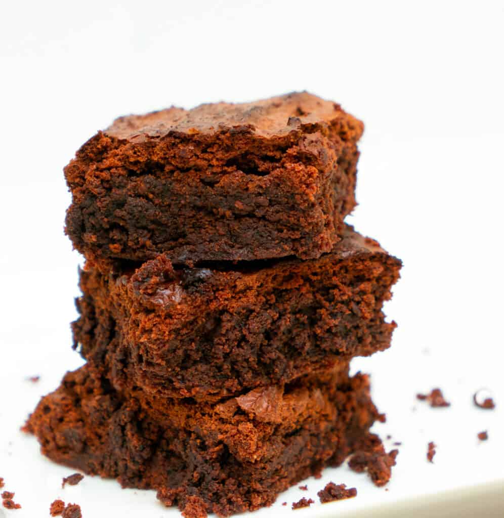 keto coconut flour brownies stacked on a white plate