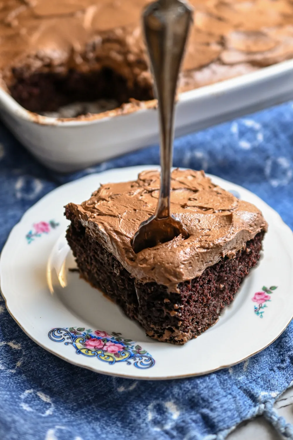 Keto Hershey's chocolate cake served on a small white plate with a fork standing in the center of the slice