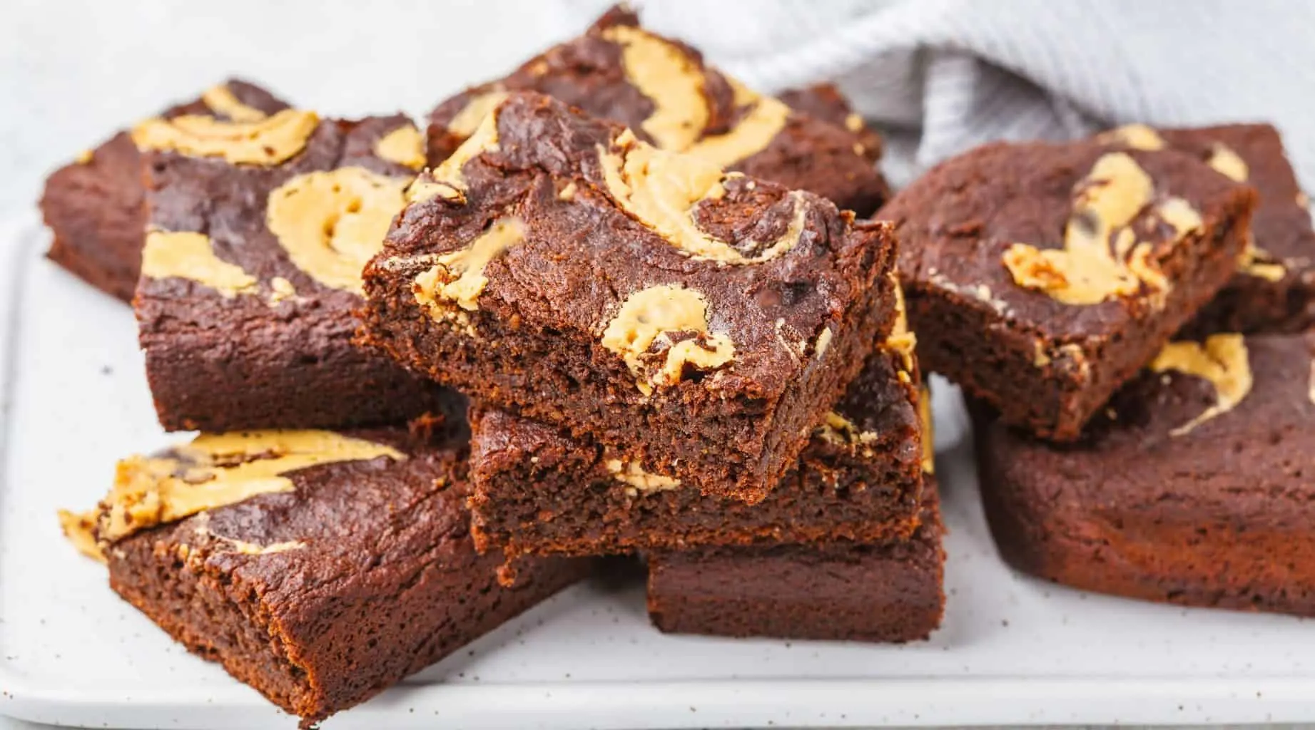 keto peanut butter swirl brownies stacked on a white tray