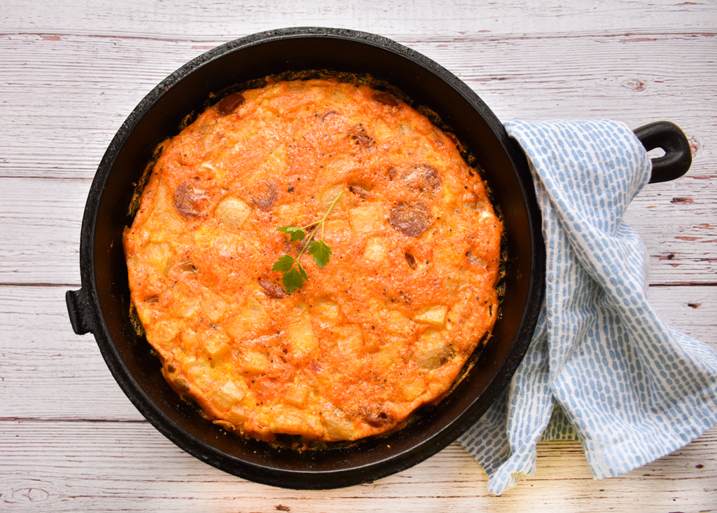 keto frittata in a cast iron skillet with a blue towel