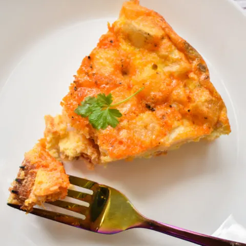 keto frittata slice with a fork in it on a white plate close up