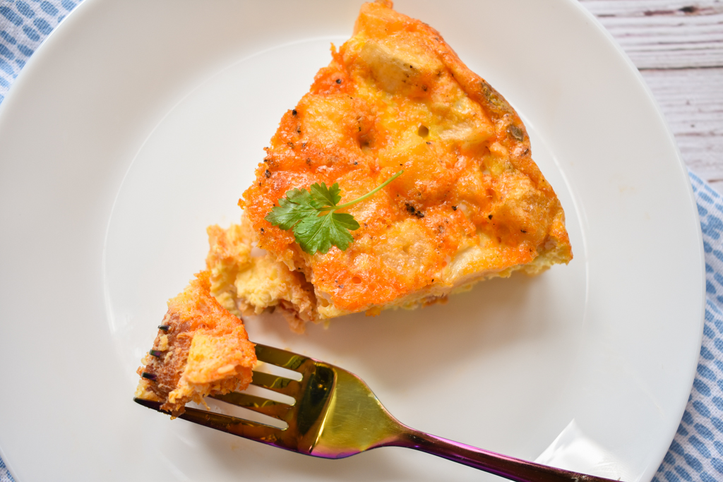 keto frittata slice with a fork in it on a white plate close up