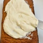 keto pumpkin bread with cream cheese frosting being added to the top