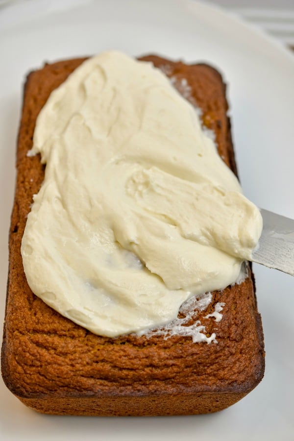 keto pumpkin bread with cream cheese frosting being added to the top