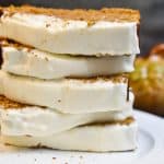 keto pumpkin bread with frosting stacked on a white pate