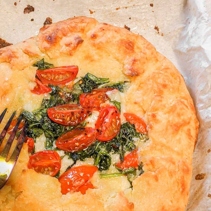 Keto Freeform Pizza Up Close With Fork On Parchment Paper
