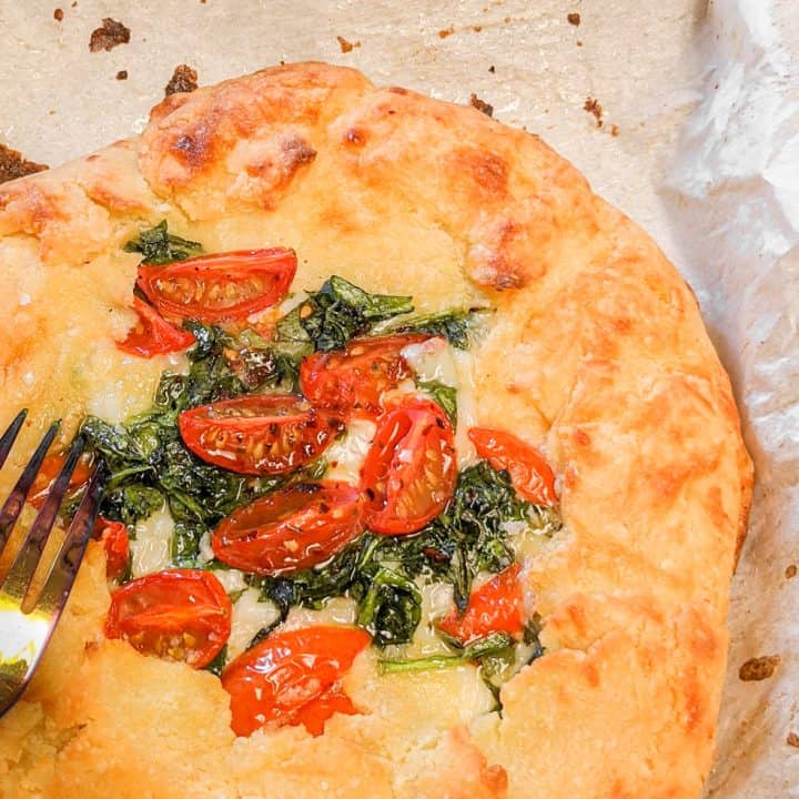 Keto Freeform Pizza Up Close With Fork On Parchment Paper