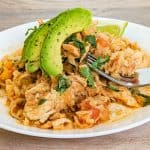Keto Mexican Cauliflower Rice and Chicken Topped with Avocado on white plate with fork fit to serve