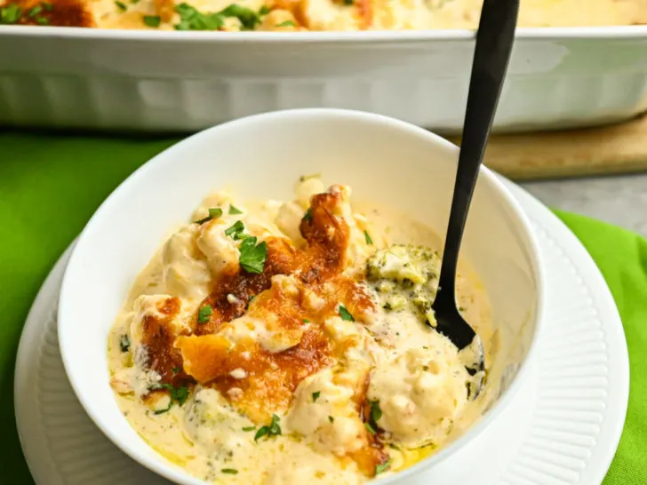 keto friendly cauliflower broccoli mac & cheese served in a white bowl with a green napkin underneath