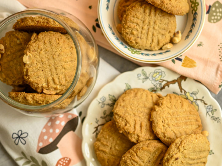 Almond flour peanut butter cookies displayed in different size plates and inside a clear cookie jar