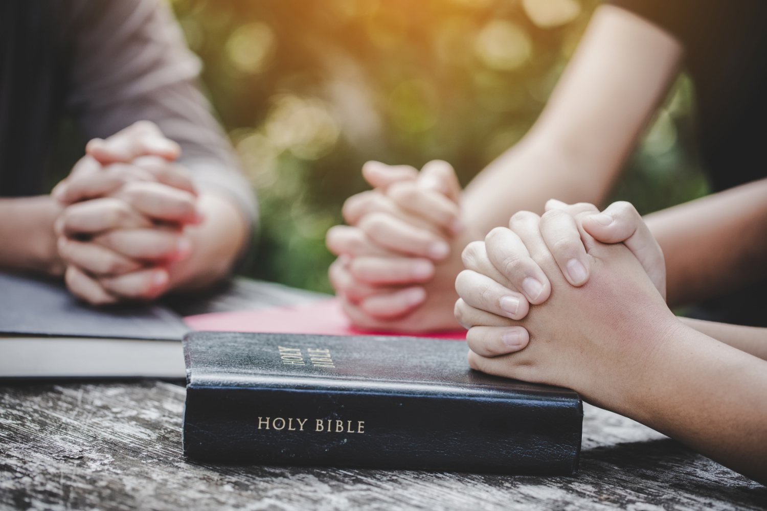 small group with folded hands in prayer