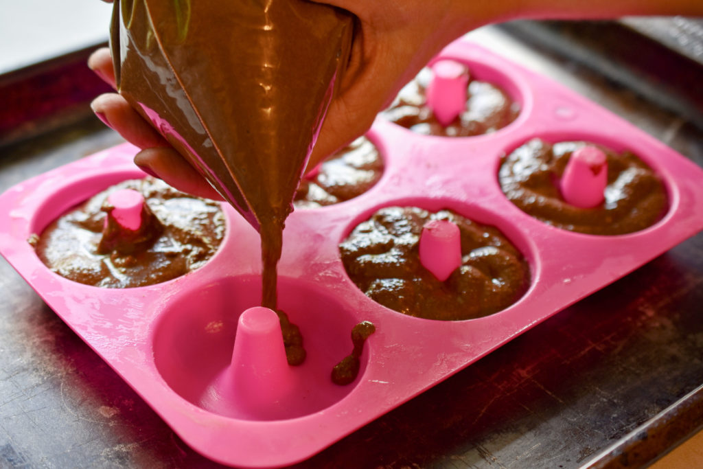 keto chocolate donuts batter being added to a silicone donut mold