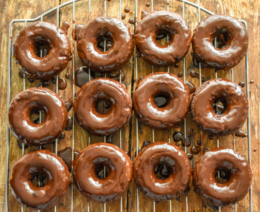 keto chocolate donuts resting on a baking rack after the chocolate icing was added