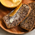 three keto high fiber bread slices with butter on a wooden plate
