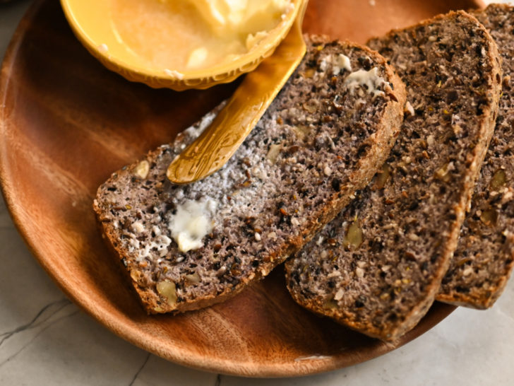 three keto high fiber bread slices with butter on a wooden plate
