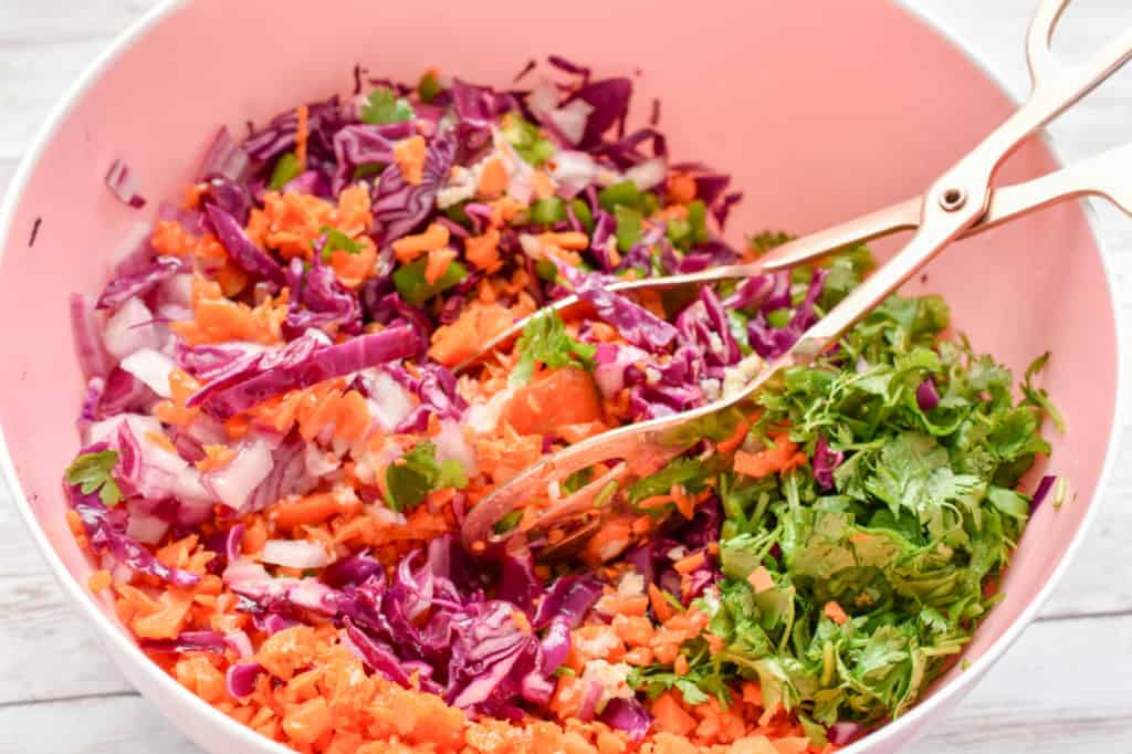 keto red cabbage and carrot slaw being made in a pink bowl