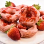 keto strawberry donuts stacked on white cake plate