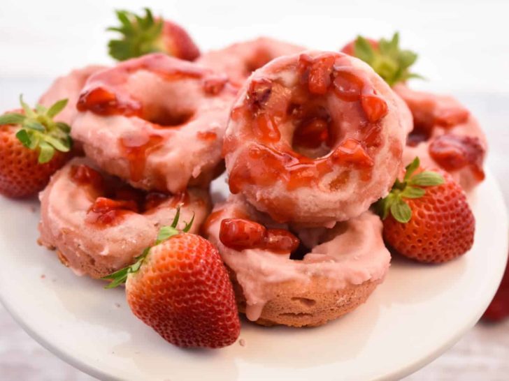 keto strawberry donuts stacked on white cake plate