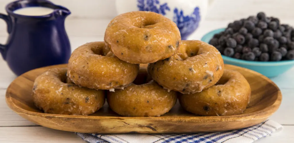 keto blueberry donuts stacked on a wooden tray