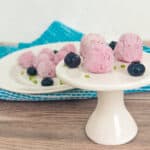 keto blueberry cream cheese fat bombs on a small white plate stand