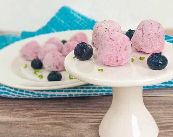 keto blueberry cream cheese fat bombs on a small white plate stand