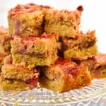 keto peanut butter jelly bars stacked on a clear cake plate