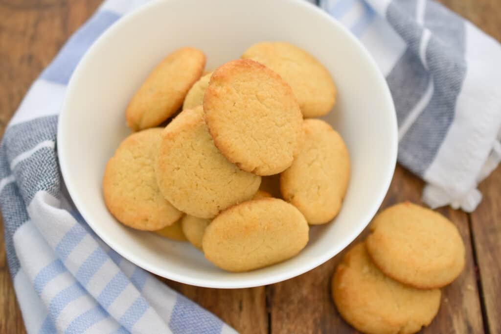 keto vanilla wafers in a white bowl with a blue and white cloth napkin next to it