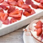 It's a picture of no bake keto cheesecake made in a rectangle pan topped with fresh strawberries