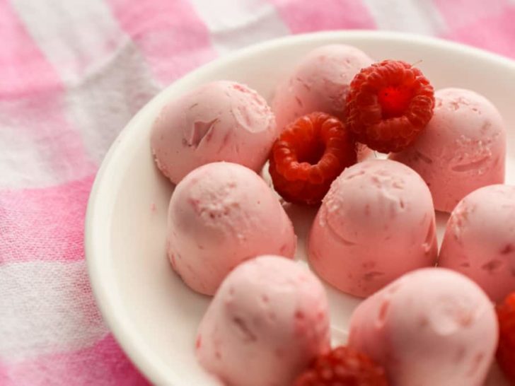 Keto Raspberry Cheesecake Fat Bombs on White Plate with Gingham Background