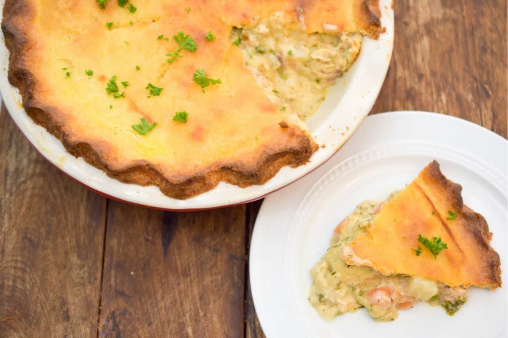 keto chicken pot pie sliced and ready to serve pie is on top of a wood table and pie is served on a white plate