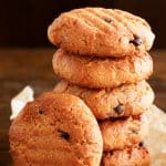 keto peanut butter chocolate chip cookies stacked on top of brown parchment paper