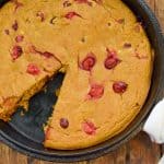 keto pumpkin cranberry cake on wood board with a slice missing